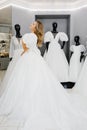 Pretty young woman is choosing a wedding dress in the shop. The bride-to-be is wearing a wedding dress for fitting Royalty Free Stock Photo