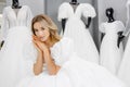 Pretty young woman is choosing a wedding dress in the shop. The bride-to-be is wearing a wedding dress for fitting Royalty Free Stock Photo