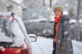 Pretty, young woman cleaning her car from snow after heavy snowstorm Royalty Free Stock Photo