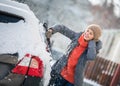 Pretty, young woman cleaning her car from snow after heavy snowstorm Royalty Free Stock Photo