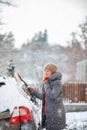 Pretty, young woman cleaning her car from snow after heavy snowstorm Royalty Free Stock Photo