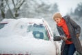 Pretty, young woman cleaning her car from snow Royalty Free Stock Photo