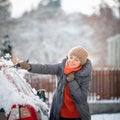 Pretty, young woman cleaning her car from snow Royalty Free Stock Photo