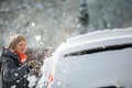 Pretty, young woman cleaning her car from snow after heavy snowstorm Royalty Free Stock Photo