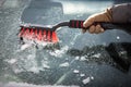 Pretty, young woman cleaning her car from snow after heavy snowstorm Royalty Free Stock Photo