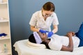 Pretty young woman cosmetologist cleaning face og beautiful African girl, lying on the table in spa