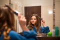 Pretty, young woman curling her hair in front of her bathroom Royalty Free Stock Photo