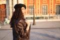 Pretty young woman with curly brown hair wearing a black cap and dressed in a leather jacket, jeans and white boots. She is Royalty Free Stock Photo