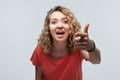 Pretty Young woman with curly hair looking at the camera and pointing her finger at you. Human emotions concept Royalty Free Stock Photo