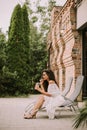 A young woman with curly hair relaxes on a deck chair and enjoys a glass of fresh lemonade Royalty Free Stock Photo