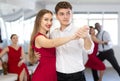 Pretty young woman dancing waltz with partner at group of multinational people in ballroom dancing class Royalty Free Stock Photo