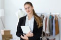 Pretty young woman designer looking at camera while holding her digital tablet in sewing workshop Royalty Free Stock Photo