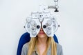 Pretty young woman doing eyesight measurement with optical phoropter in ophthalmology clinic