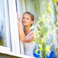 Pretty, young woman doing house work - washing windows Royalty Free Stock Photo