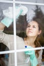 Pretty, young woman doing house work - washing windows Royalty Free Stock Photo