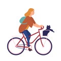 Pretty young woman dressed in casual clothes riding bike with cat sitting in basket. Cute girl on bicycle with her pet Royalty Free Stock Photo