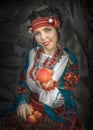 A pretty young woman dressed in a Ukrainian folk costume sitting and holding apples. Cosplay