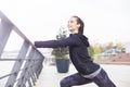 Pretty young woman with earphones stretching during sport training