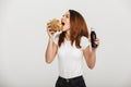 Pretty young woman eating burger drinking soda.