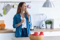 Pretty young woman eating yogurt while standing in the kitchen at home Royalty Free Stock Photo