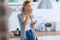 Pretty young woman eating yogurt while standing in the kitchen at home Royalty Free Stock Photo