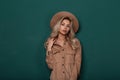 Pretty young woman in an elegant vintage hat in a stylish shirt with curly blond hair is standing in the studio Royalty Free Stock Photo