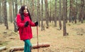 A pretty young woman is engaged in the nordic walking in woods.