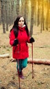 A pretty young woman is engaged in the nordic walking in woods. Royalty Free Stock Photo