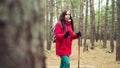 A pretty young woman is engaged in the nordic walking in woods.