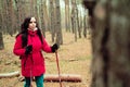 A pretty young woman is engaged in the nordic walking in woods.