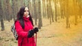 A pretty young woman is engaged in the nordic walking in woods.