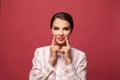 Pretty young woman giggles positively at camera, dressed in casual shirt, shows beauty on red background