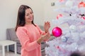 Pretty young woman is glad to decorate a Christmas tree, enjoying holiday spirit. Royalty Free Stock Photo