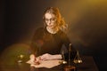 Pretty young woman in a glasses and in a black dress sitting and wrighting importaint document Royalty Free Stock Photo