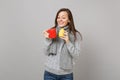 Pretty young woman in gray sweater, scarf holding lemon, red cup of tea isolated on grey wall background. Healthy Royalty Free Stock Photo