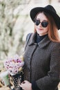 Pretty young woman in hat posing with coffee and flowers in bag Royalty Free Stock Photo