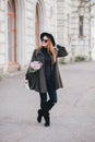 Pretty young woman in hat posing with coffee and flowers in bag Royalty Free Stock Photo