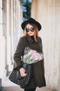 Pretty young woman in hat posing with flowers in bag Royalty Free Stock Photo