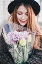 Pretty young woman in hat posing with flowers in bag Royalty Free Stock Photo