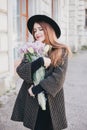 Pretty young woman in hat posing with flowers in bag Royalty Free Stock Photo