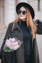 Pretty young woman in hat posing with flowers in bag Royalty Free Stock Photo
