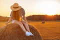 Pretty young woman in hat sitting on a hay bale Royalty Free Stock Photo