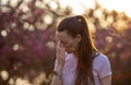 Girl sneezing in front of blooming tree in spring