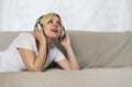 Pretty young woman in headphones lying on sofa listening music or audio book with closed eyes. Joyful beautiful lady enjoying popu Royalty Free Stock Photo