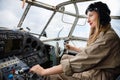 Pretty young woman in a helmet and pilot`s suit sits in the cabin