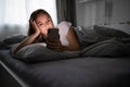 Pretty, young woman  in her bed with her cell phone Royalty Free Stock Photo