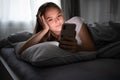 Pretty, young woman in her bed with her cell phone Royalty Free Stock Photo