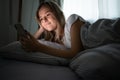 Pretty, young woman in her bed with her cell phone Royalty Free Stock Photo