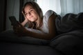 Pretty, young woman in her bed with her cell phone Royalty Free Stock Photo