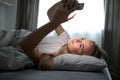Pretty, young woman  in her bed with her cell phone Royalty Free Stock Photo
